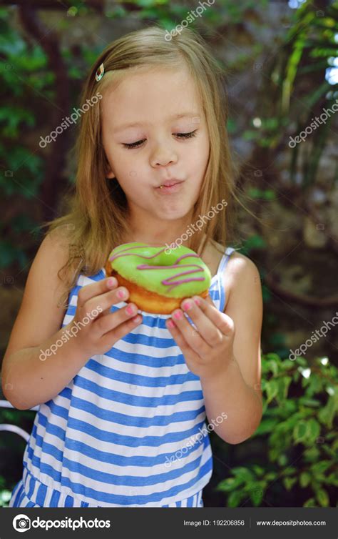 linda niña comiendo rosquillas dulces aire libre fotografía de stock © reanas 192206856