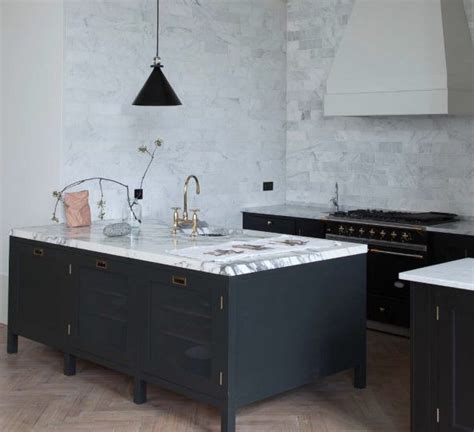 A Kitchen With Marble Counter Tops And Black Cabinets Along With An