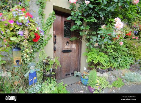 Roses And Summer Flowers Grow Around The Front Door Of A Traditional