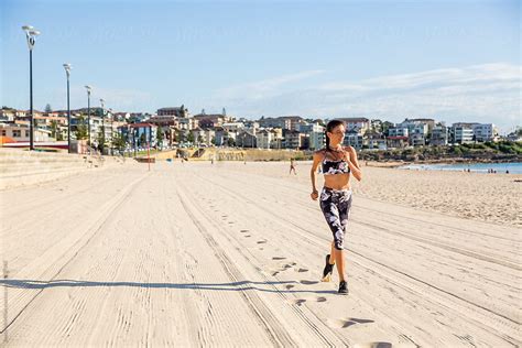 A Fit Woman Running Along The Beach By Stocksy Contributor Reece McMillan Stocksy