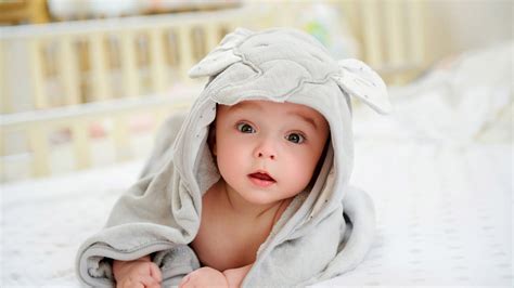 Cute Child Baby Is Lying Down On White Bed Covered With