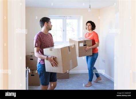 Couple Moving Into New Home Carrying Cardboard Boxes Stock Photo Alamy