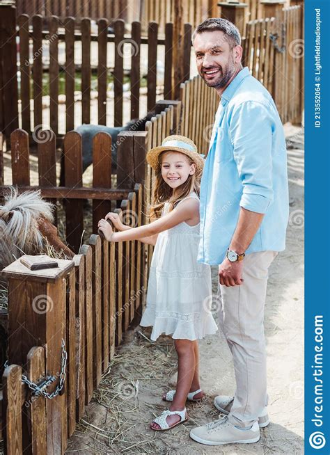 Cheerful Kid And Man Smiling While Standing Near Pony In Zoo Stock