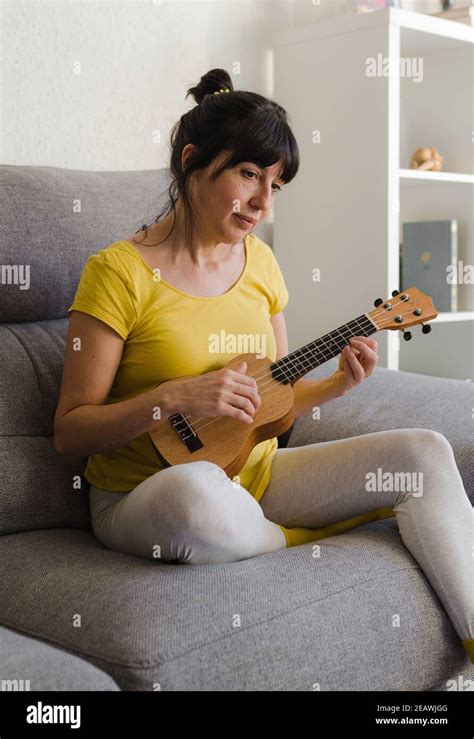 Young Brunette Woman With Her Hair Tied Back Playing The Ukulele