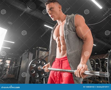 Man Doing Exercise For Bicepses With Barbell In Gym Stock Photo