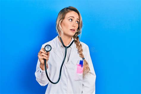 Beautiful Young Blonde Doctor Woman Holding Stethoscope Looking Sleepy