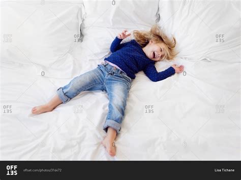 Little Girl Lying Down And Laughing On A White Bed Stock Photo Offset