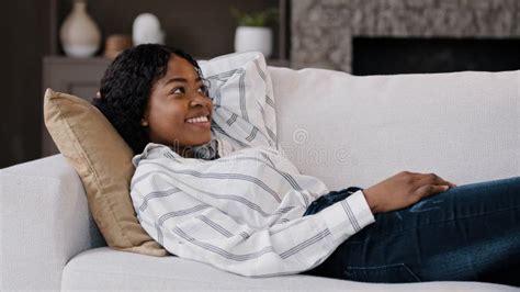 Happy Relaxed African American Woman Rest Lounge Lying On Couch Enjoy Peaceful Mood Weekend