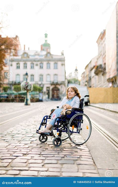 Beautiful Disabled Woman In Wheelchair Smiling At Camera While Walking