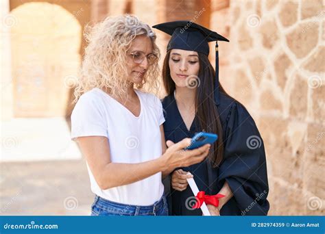 two women mother and graduated daughter using smartphone at campus university stock image