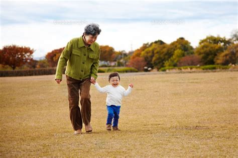 芝生の上でおばあちゃんと手をつないで散歩する孫 10132105513 ｜ 写真素材・ストックフォト・画像・イラスト素材｜アマナイメージズ