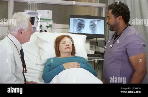 a male nurse discusses x rays with the husband as the wife is unconscious stock video footage