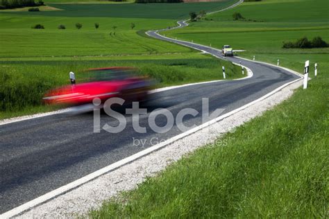 Red Car Driving On Winding Road In Spring Landscape Stock Photo