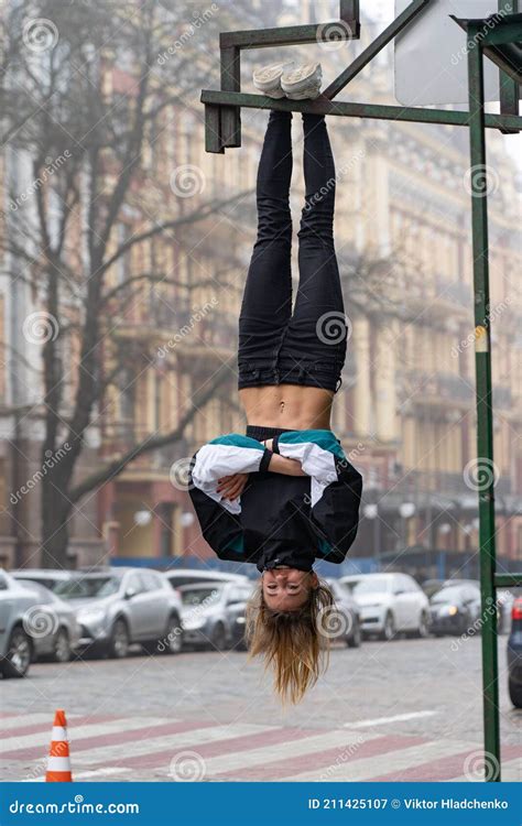 Young Attractive Girl Hanging By Feet Upside Down In The Street Stock