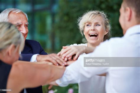 Cheerful Businesswoman With Colleagues Stacking Hands In City High Res