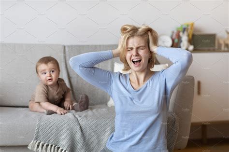 Stressed Mother Having Headache With Baby At Home Stock Photos