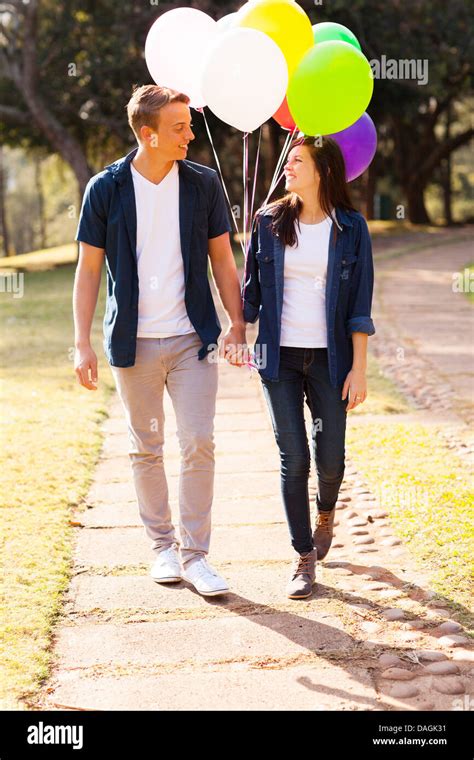 Adorable Teenage Couple Walking At The Park Holding Hands Stock Photo