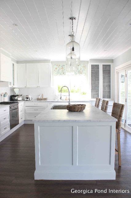 With drawer refrigerator and freezer on island. White kitchen cabinets, white shiplap ceiling, dark wood ...