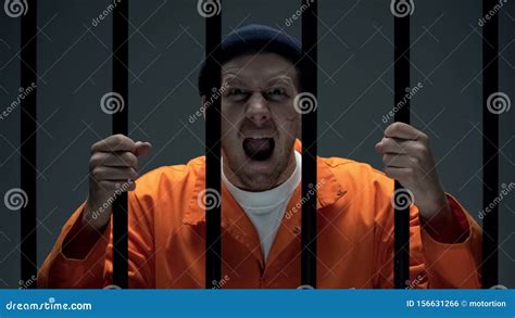 Aggressive Dangerous Male Prisoner With Scar On Face Holding Bars And