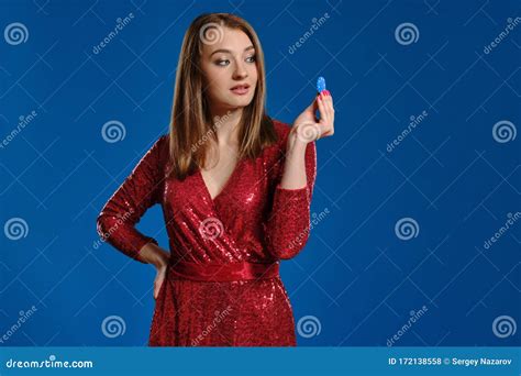 Blonde Female With Make Up In Red Sequin Dress Is Showing One Chip Posing On Blue Background