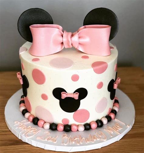 A Minnie Mouse Birthday Cake With Pink And Black Polka Dots On The Top Topped With A Bow