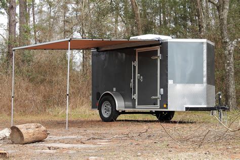 An Enclosed Trailer Parked In The Middle Of A Wooded Area With A Canopy