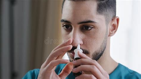 Portrait Of Sick Caucasian Man Doctor In Nurse Medical Uniform Treating Runny Nose Using Nasal