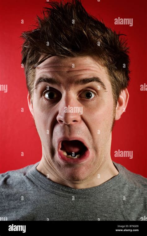 Young Man With Shocked Expression Against Red Background Stock Photo