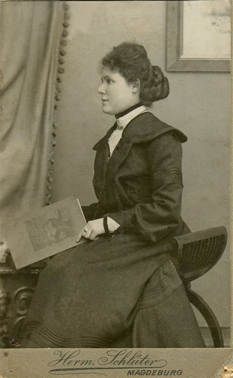 An Old Black And White Photo Of A Woman Holding A Book