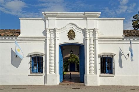 An Entrance To A White Building With Blue Shutters And Flags Hanging From The Front