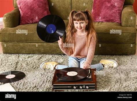 Cute Little Girl Listening To Music Through Record Player At Home Stock