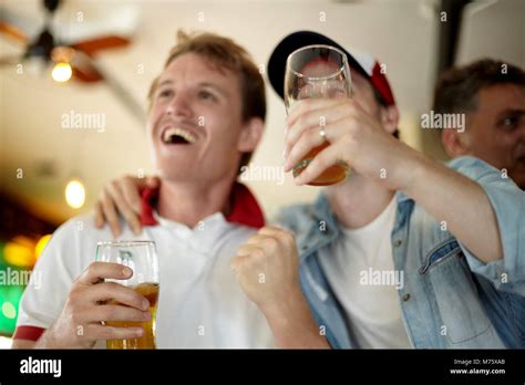 Sports enthusiasts watching match together in bar Stock Photo - Alamy