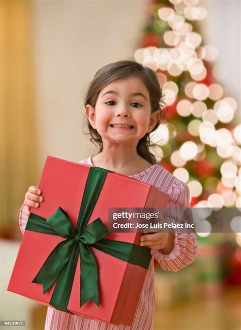 Curious Young Girl Holding Large Christmas T High Res Stock Photo