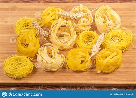 Different Uncooked Pasta Nests And Wheat Ears On Cutting Board Stock