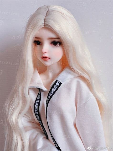 A Doll With Long Blonde Hair Wearing A White Shirt