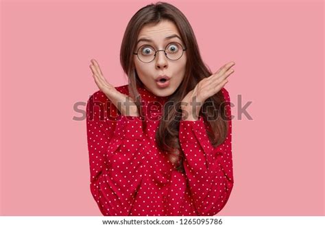 Puzzled Woman With Dark Hair Spreads Hands Has Shocked Facial Expression Expresses