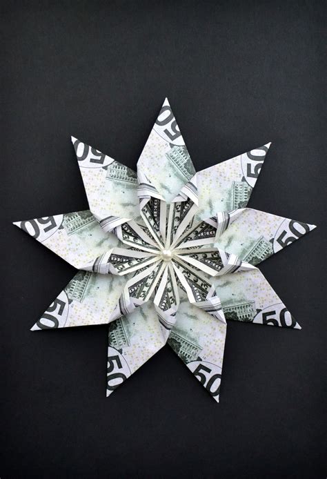 An Origami Snowflake Made Out Of Money On A Black Background Photo
