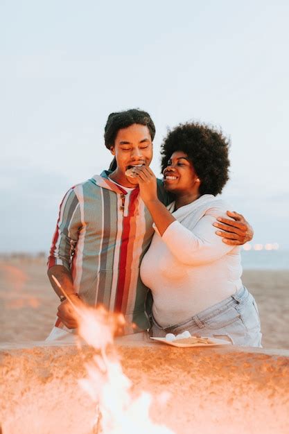 Premium Photo Couple Roasting Marshmallows Over A Bonfire