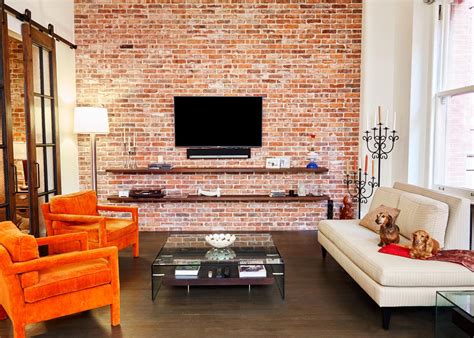 A brick wall makes the staircase stand out in this industrial space. Midcentury Loft Living Room With Brick Wall | HGTV