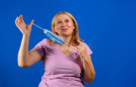 middle blonde woman taking off her medical mask isolated on blue background stock image image