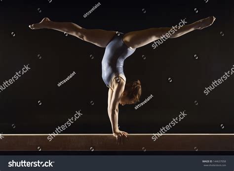 Side View Of A Female Gymnast Doing Split Handstand On Balance Beam
