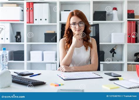 Beautiful Young Girl Is Sitting At The Desk In The Office Stock Image