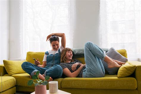 Two Woman Sitting On A Couch In A Cosy Small Living Room Relaxing
