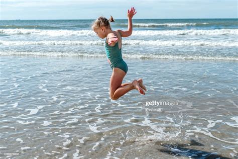 Girl Gymnast Jumping Over Sea At Beach On Sunny Day High Res Stock