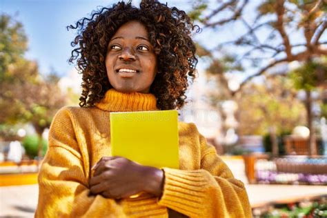 African American Woman Smiling Confident Holding Book At Park Stock