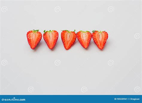 Fresh Organic Strawberries Halved And Arranged In A Line On A White