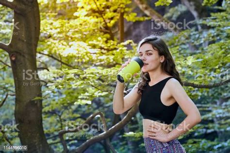 Healthy Fitness Girl Drinking Water From Green Bottle In Forrest Stock