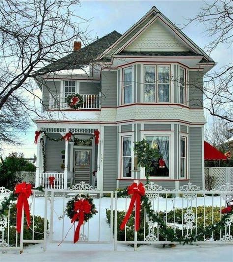 A House Decorated For Christmas With Wreaths And Bows On The Front