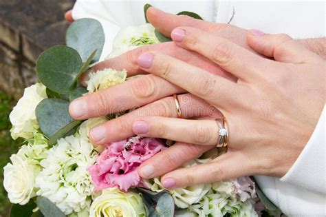 Bride And Groom Hands Wedding Fingers Rings Close Up On Bouquet Flowers