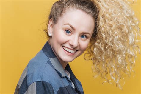 Sideways Shot Of Pleased Adorable Young Female Model With Curly Hair